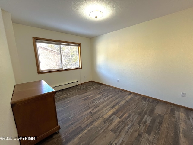 spare room featuring dark hardwood / wood-style flooring and a baseboard heating unit