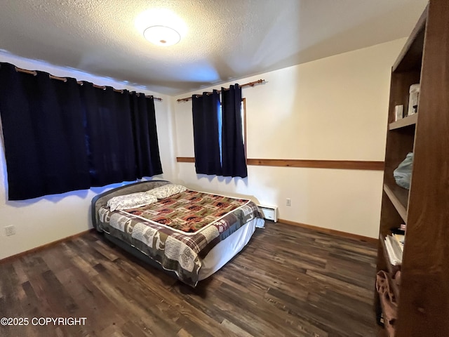 bedroom with a baseboard radiator, dark hardwood / wood-style flooring, and a textured ceiling