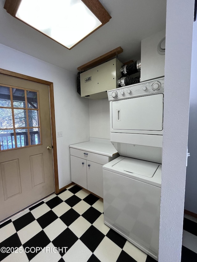 laundry room featuring cabinets and stacked washer / drying machine