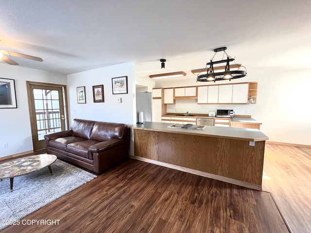 kitchen featuring sink, dark wood-type flooring, kitchen peninsula, and appliances with stainless steel finishes