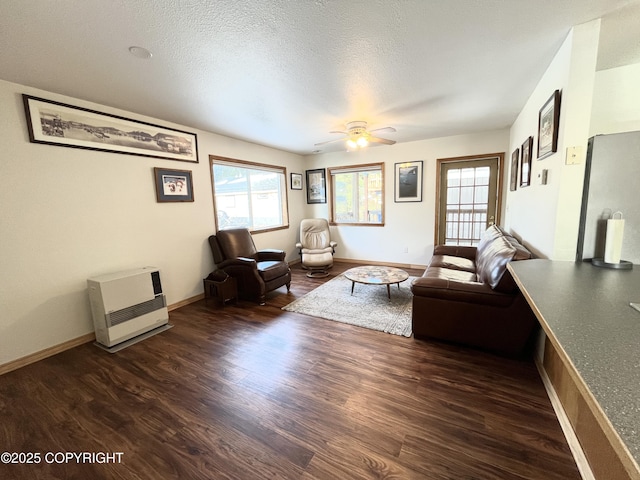 unfurnished living room with ceiling fan, dark hardwood / wood-style flooring, heating unit, and a textured ceiling