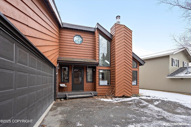 snow covered property entrance featuring a garage