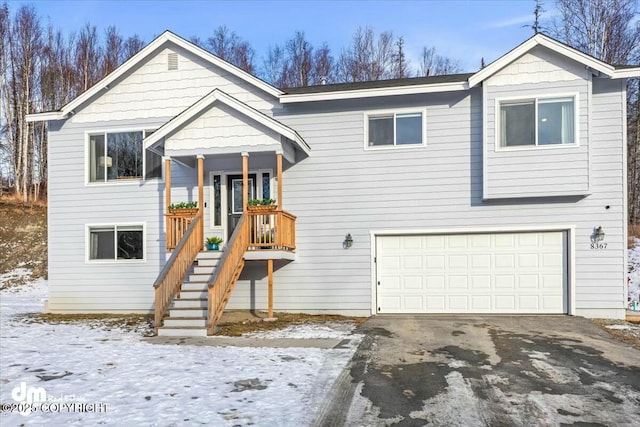 bi-level home featuring an attached garage, driveway, and stairway