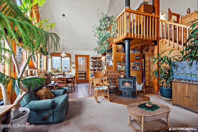 carpeted living area featuring a wood stove, a high ceiling, and tile patterned floors