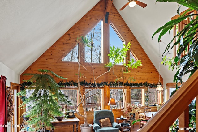 interior space with a ceiling fan and wooden walls