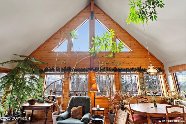 dining room with high vaulted ceiling and wood walls