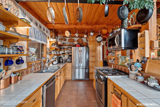 kitchen with tile patterned flooring, a sink, appliances with stainless steel finishes, tile counters, and open shelves