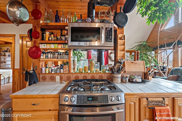 kitchen featuring a healthy amount of sunlight, wallpapered walls, tile counters, and stainless steel appliances