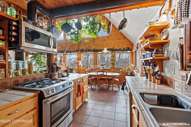 kitchen featuring open shelves, appliances with stainless steel finishes, a sink, and tile counters