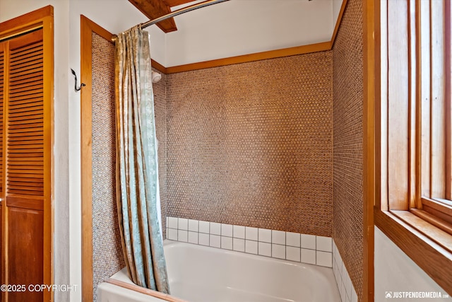 bathroom featuring a closet and shower / tub combo with curtain