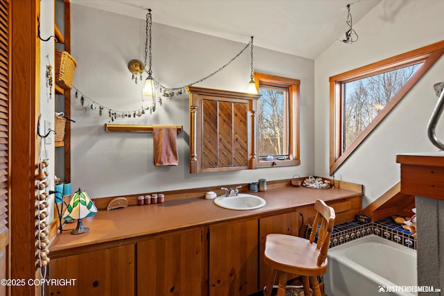 bathroom featuring lofted ceiling, vanity, and a bath