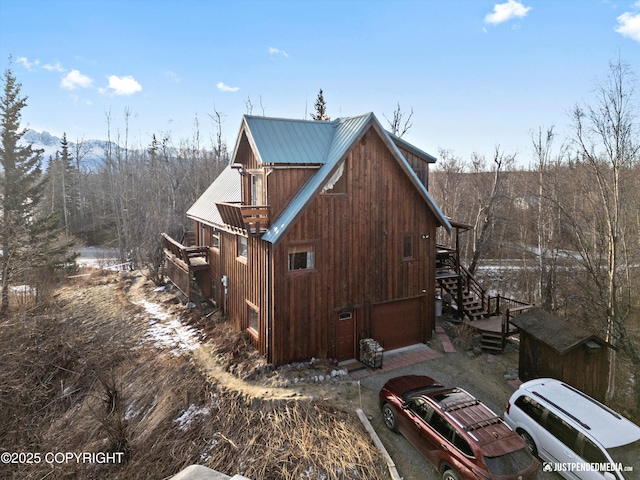 view of side of home featuring stairway and metal roof