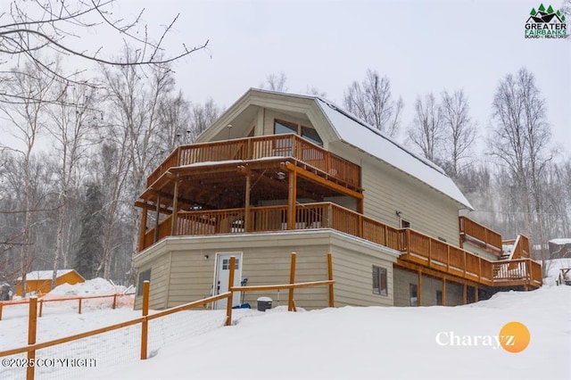 snow covered back of property with a wooden deck