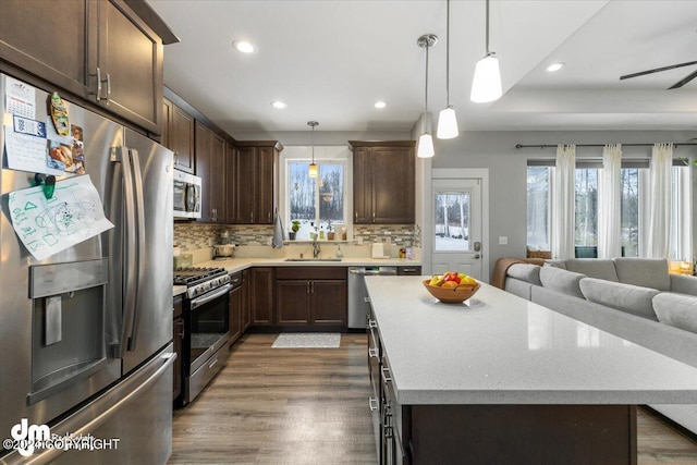 kitchen with stainless steel appliances, decorative light fixtures, and a center island