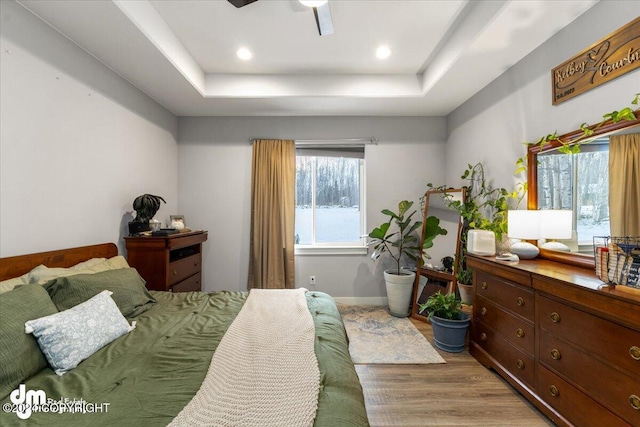 bedroom featuring a tray ceiling and light wood-type flooring