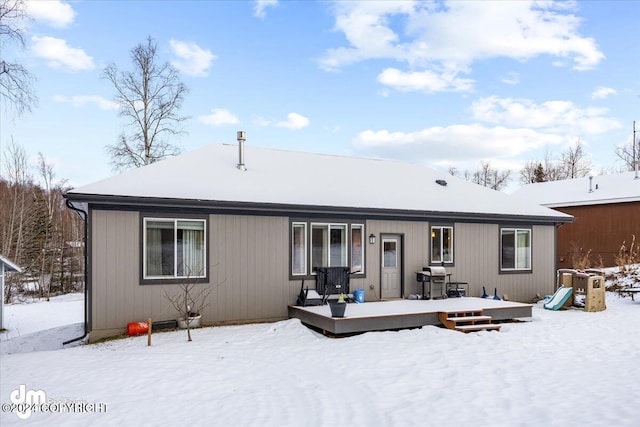 snow covered property featuring a playground and a deck