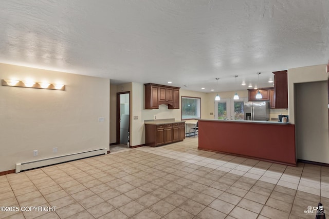 kitchen with light tile patterned flooring, a textured ceiling, hanging light fixtures, stainless steel fridge, and a baseboard heating unit