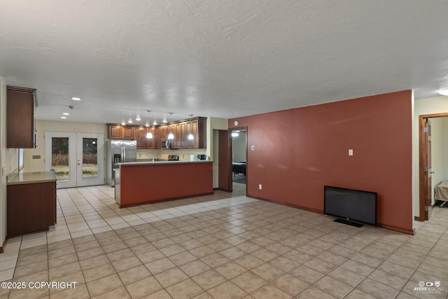 kitchen with french doors, a textured ceiling, appliances with stainless steel finishes, kitchen peninsula, and pendant lighting