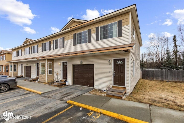 townhome / multi-family property featuring entry steps, an attached garage, and fence