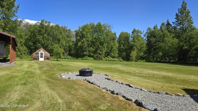 5853 E Edgerton Parks Rd, Palmer, AK 99645 - view of grassy yard with an outdoor fire pit and an outbuilding