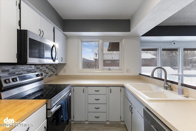 kitchen featuring light hardwood / wood-style flooring, stainless steel appliances, decorative backsplash, sink, and white cabinetry