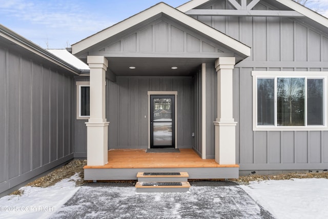 snow covered property entrance featuring board and batten siding