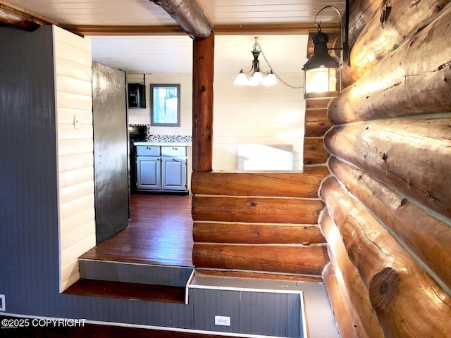 interior space featuring hanging light fixtures, beam ceiling, dark hardwood / wood-style floors, and rustic walls