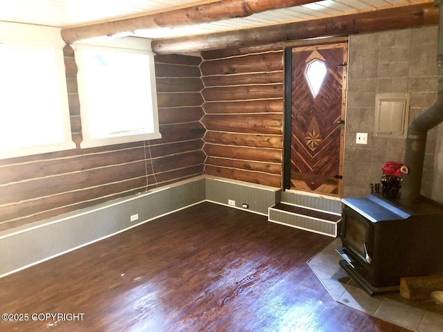 interior space featuring wood-type flooring, beamed ceiling, rustic walls, and a wood stove