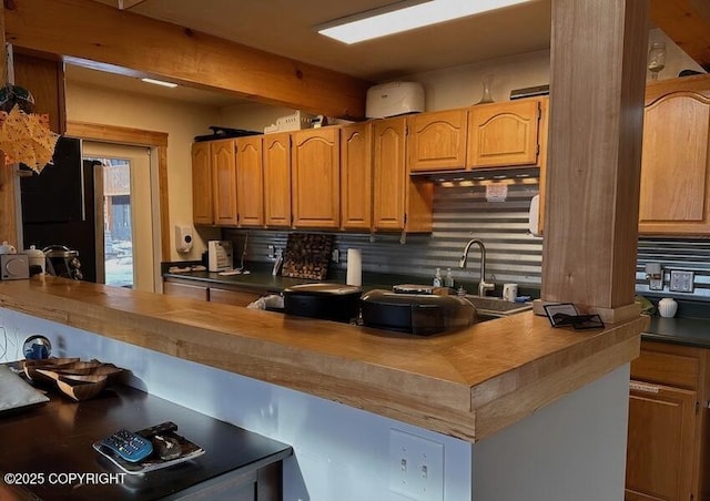 kitchen with beamed ceiling, decorative backsplash, and wooden counters