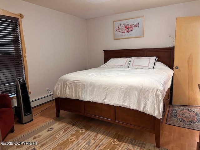 bedroom featuring baseboard heating and wood finished floors