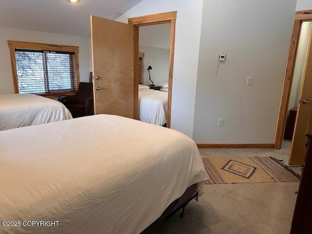 bedroom with light colored carpet, vaulted ceiling, and baseboards