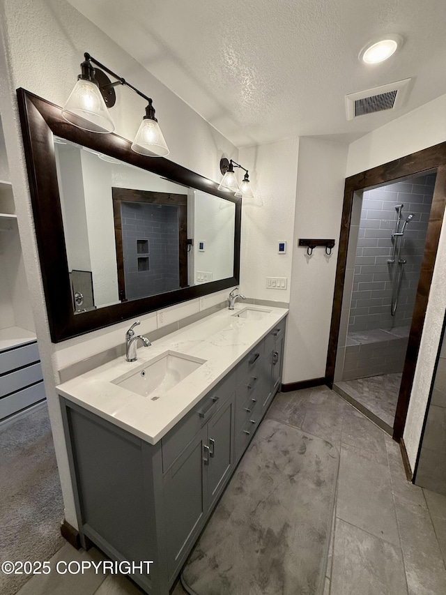 bathroom with vanity, a textured ceiling, and tiled shower