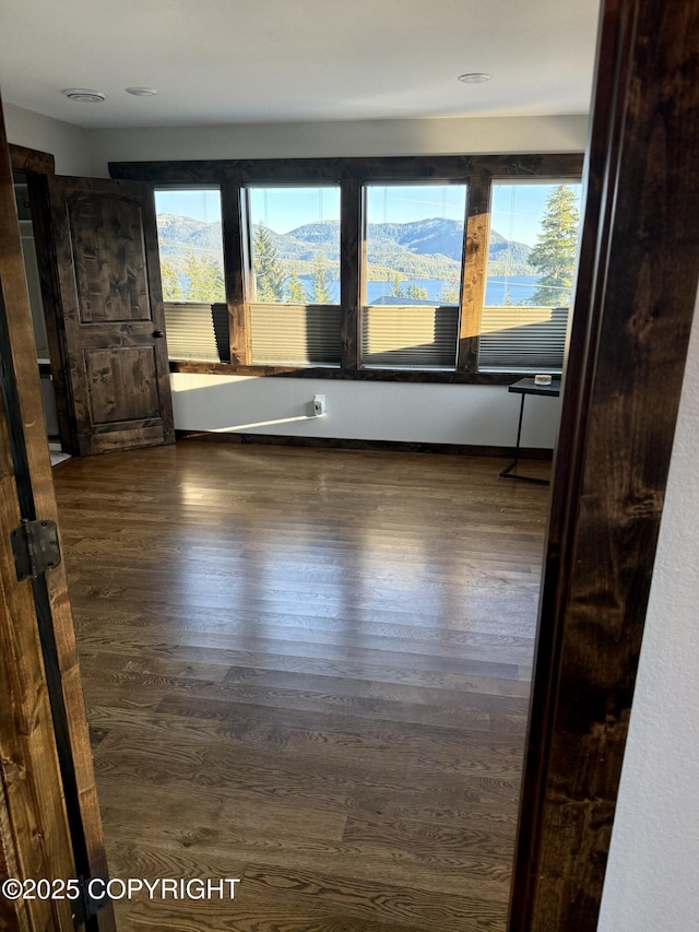 empty room with dark hardwood / wood-style flooring and a mountain view