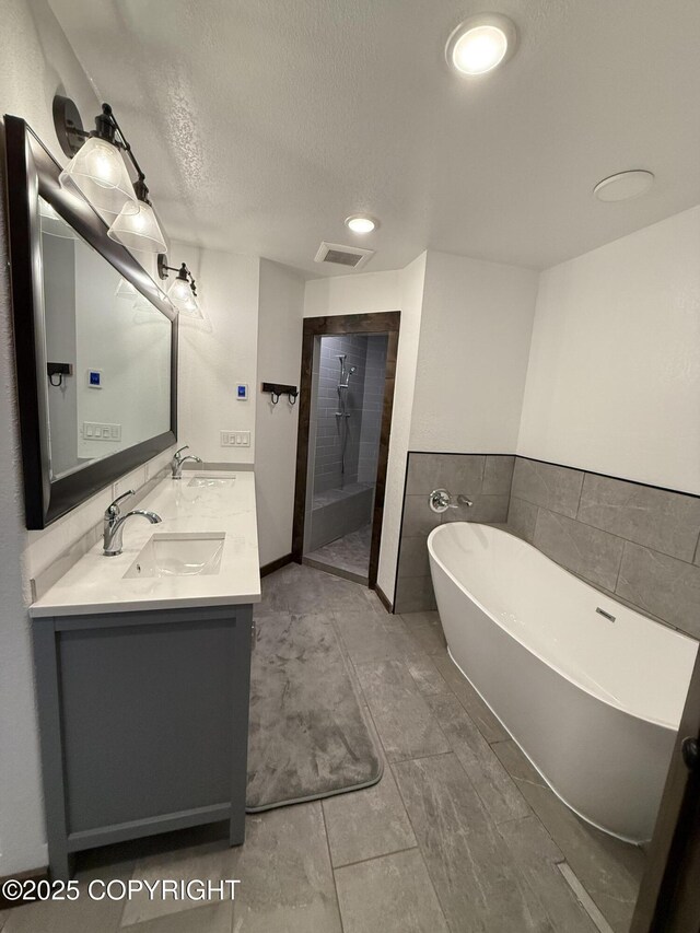 bathroom with vanity, plus walk in shower, and a textured ceiling