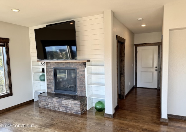 living room featuring a brick fireplace and dark wood-type flooring