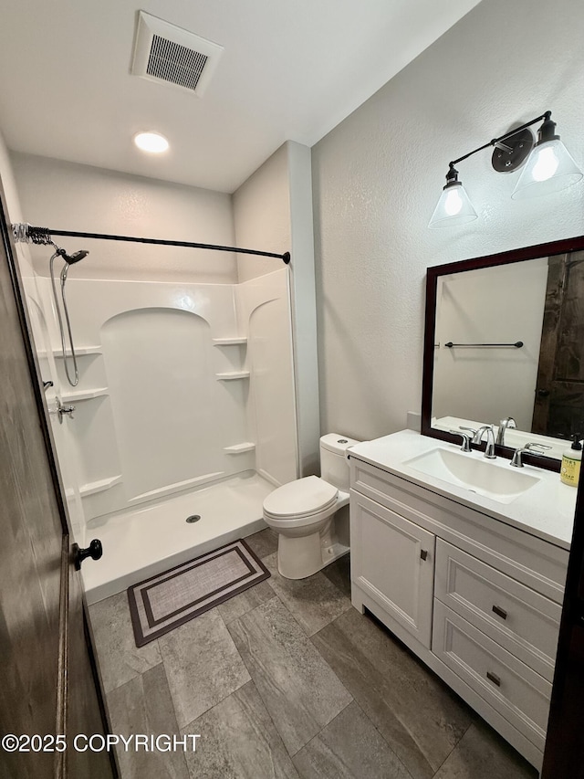 bathroom with vanity, toilet, and a shower