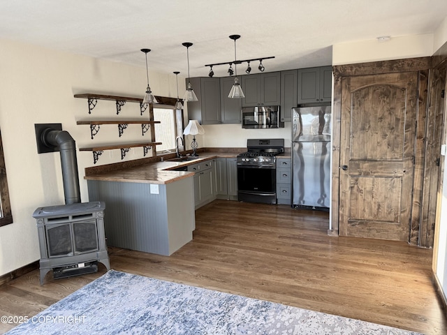 kitchen featuring dark hardwood / wood-style flooring, stainless steel appliances, decorative light fixtures, and kitchen peninsula