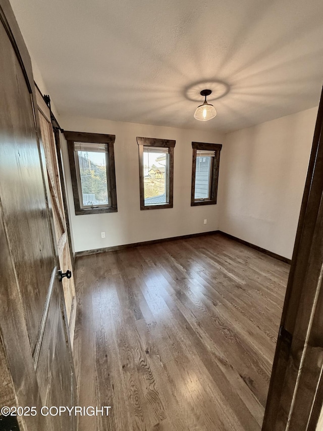 spare room with hardwood / wood-style flooring, a barn door, and a textured ceiling