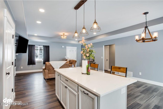 kitchen featuring pendant lighting, dark hardwood / wood-style floors, a center island, and a raised ceiling