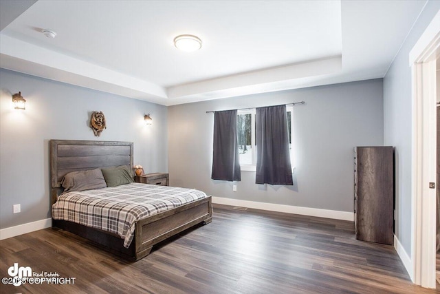 bedroom featuring dark hardwood / wood-style floors and a tray ceiling