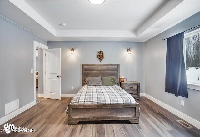 bedroom with a tray ceiling and hardwood / wood-style flooring