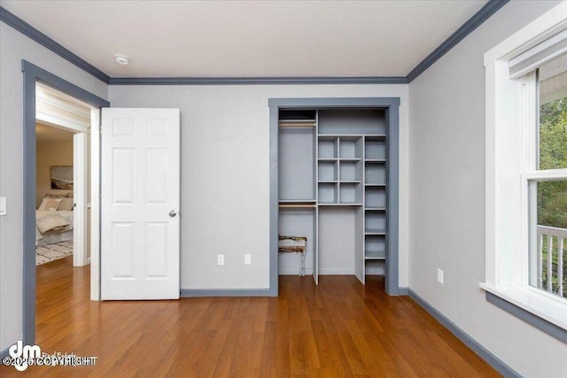 unfurnished bedroom featuring hardwood / wood-style flooring, ornamental molding, and a closet