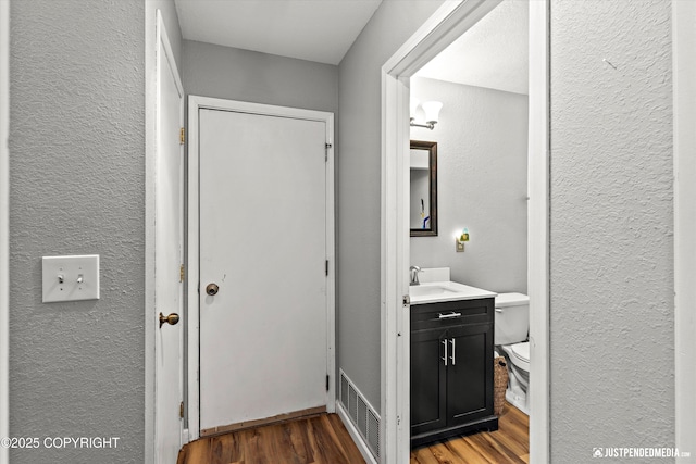 bathroom with toilet, hardwood / wood-style flooring, and vanity