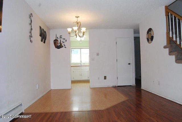 unfurnished room featuring dark wood-type flooring, a baseboard radiator, and a chandelier