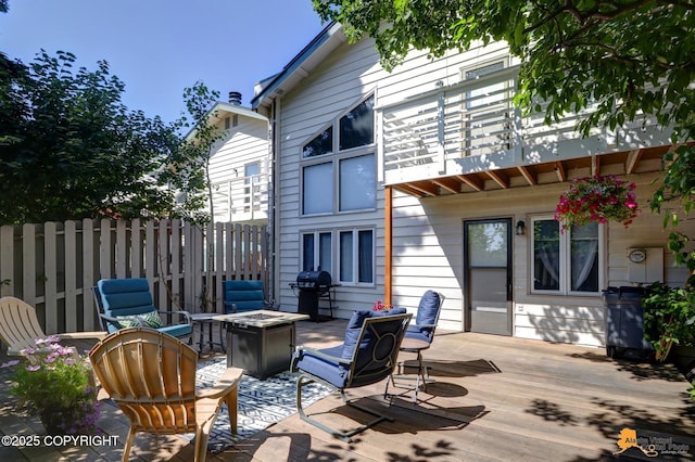 deck with a fire pit, grilling area, and fence