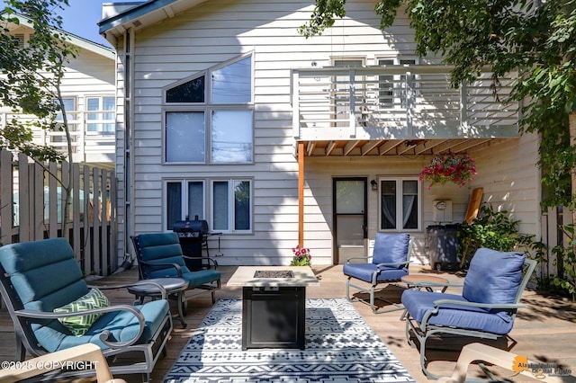 back of property with a balcony, a patio, and an outdoor living space with a fire pit