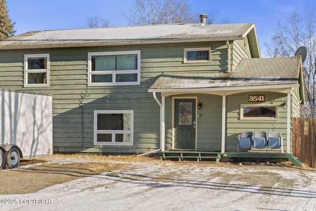 view of front of house with covered porch, roof with shingles, and fence