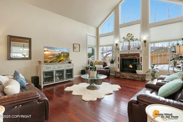 living area featuring high vaulted ceiling, dark wood-type flooring, a fireplace, and baseboards