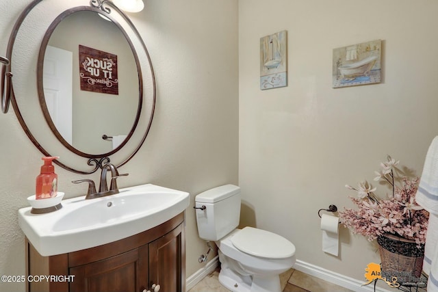 half bathroom featuring tile patterned flooring, vanity, toilet, and baseboards