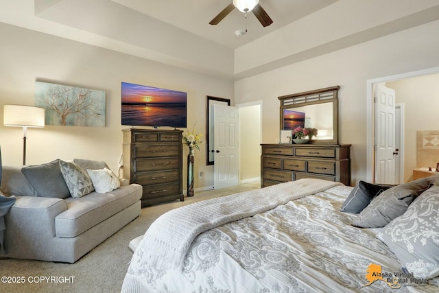 bedroom with a tray ceiling, light carpet, ceiling fan, and baseboards